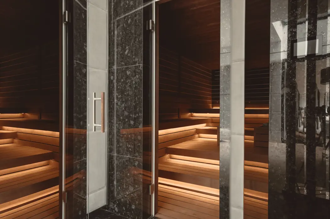 Роскошная сауна с мягким освещением, деревянными скамьями и мраморной отделкой в современном спа-интерьере.