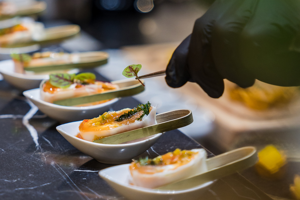 طاهٍ فاخر يزيّن المقبلات بعناية، ممزجًا بين الألوان والملمس والفن لابتكار تجربة طعام راقية لا تُنسى.