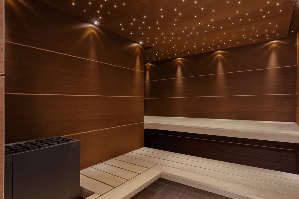Sauna en bois de luxe avec éclairage d’ambiance et plafond étoilé, offrant une atmosphère de détente et de bien-être.