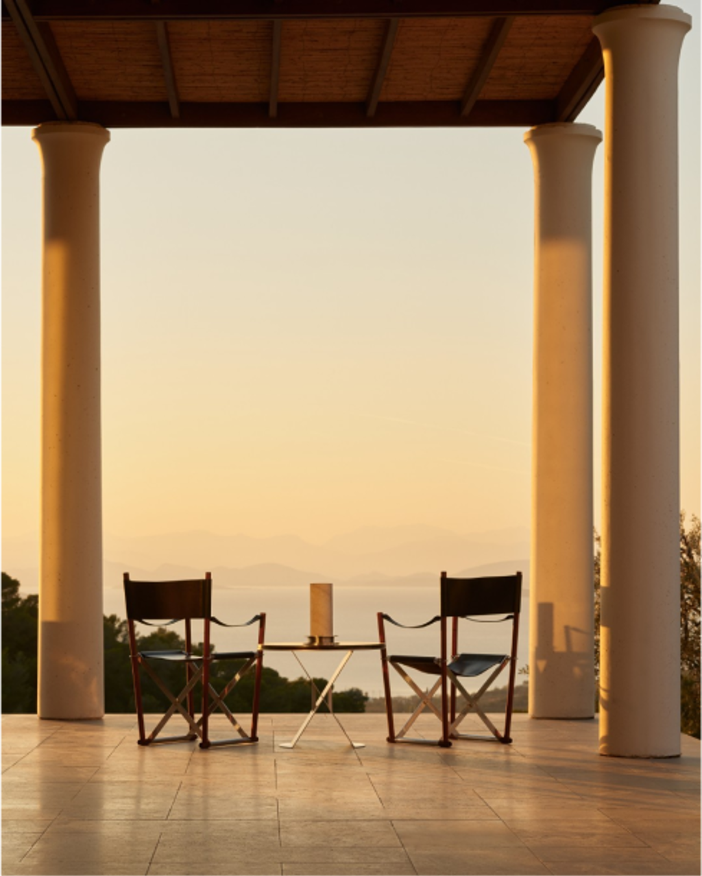 Cozy mountain lodge interior with stone fireplace, crackling fire, and cocktail table at sunset.