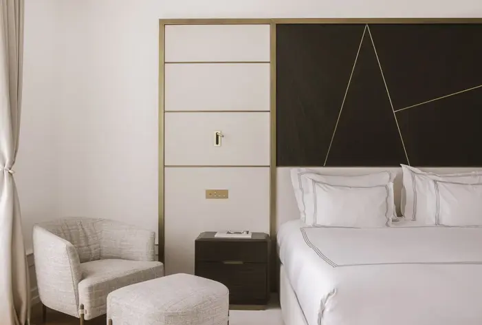 Refined bedroom with soft neutral palette, elegant bed linens, and modern geometric wall design.