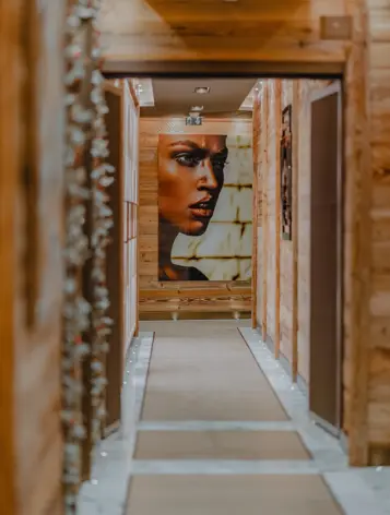Couloir intérieur moderne en bois avec un éclairage doux et un grand portrait contemporain sur le mur.