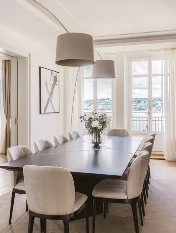 Salle à manger raffinée baignée de lumière naturelle, alliant élégance contemporaine et vue apaisante sur l’eau.