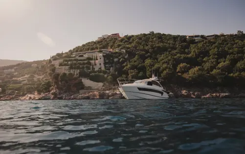 فيلا فاخرة مطلة على البحر تحيط بها الطبيعة الخضراء ويقف اليخت عند الساحل الخاص.