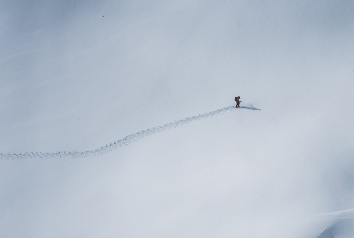 Solo skier making fresh tracks across untouched snow on a mountain slope.
