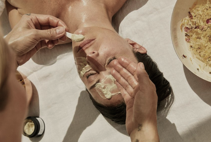 Close-up of a relaxing facial treatment with a skincare specialist applying a creamy mask to a woman’s face.